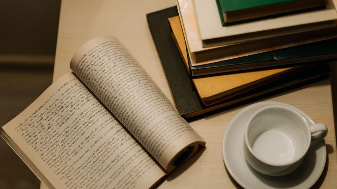 An open book and a stack of books on a table in warm light