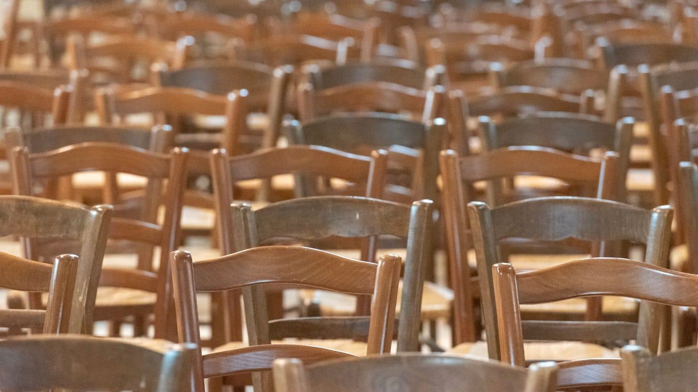Rows of wooden chairs in a warmly lit hall