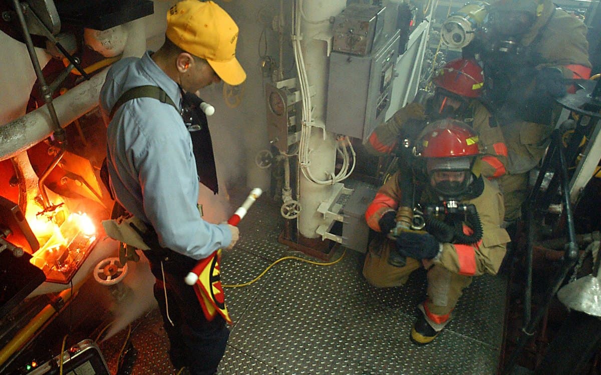 A Navy damage control team working a fire drill in a shipboard engineering space